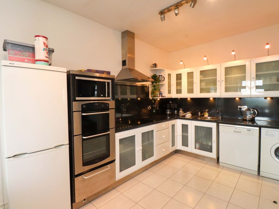 A kitchen with appliances and cabinets at Sea Views No 8 Plas Darien in Trearddur Bay