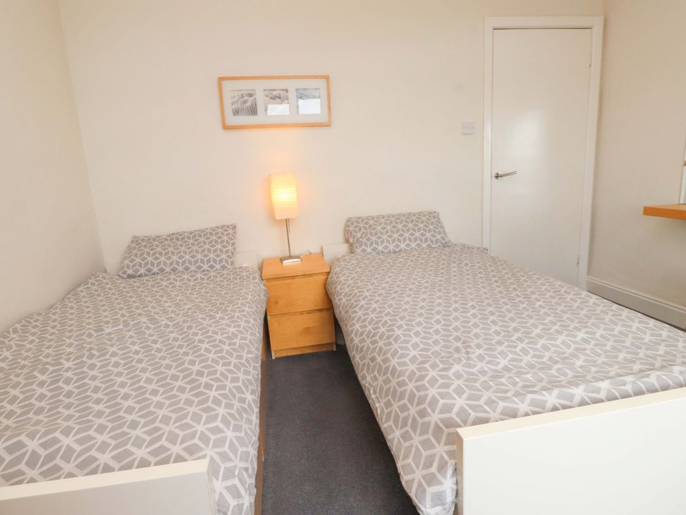 A bedroom with two single beds and a nightstand at Sea Views No 8 Plas Darien Trearddur Bay
