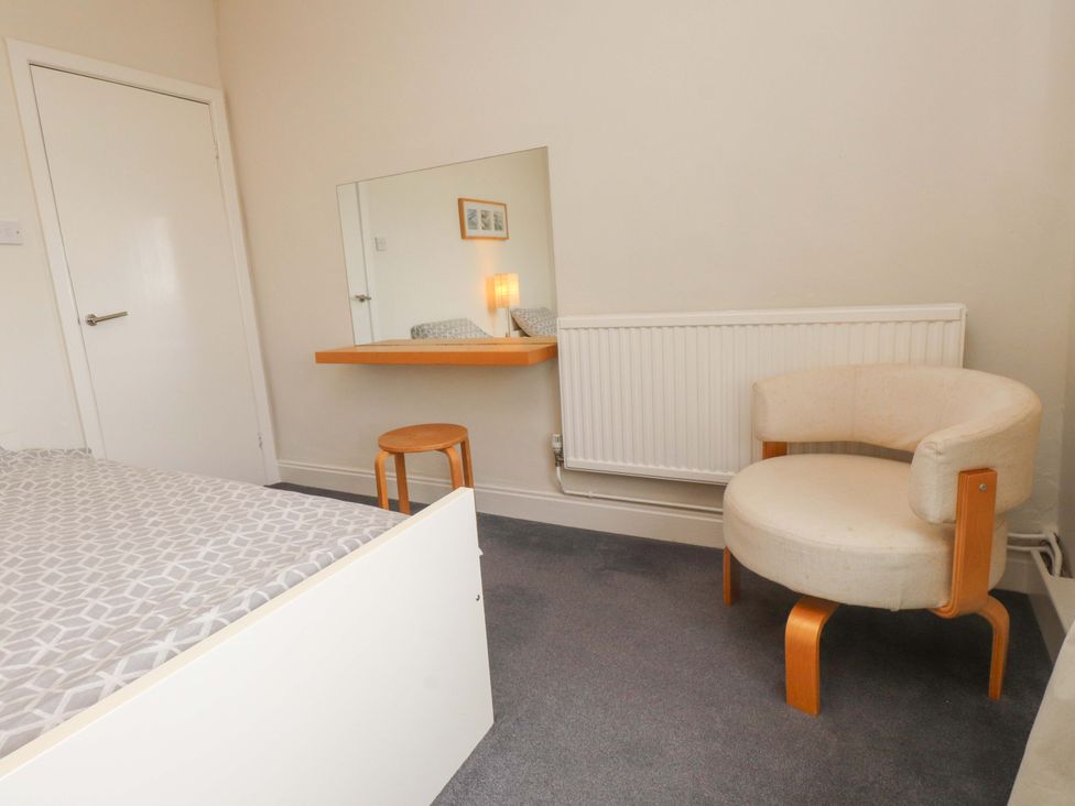A bedroom with a bed, a mirror, a chair, and a stool at Sea Views No 8 Plas Darien Trearddur Bay