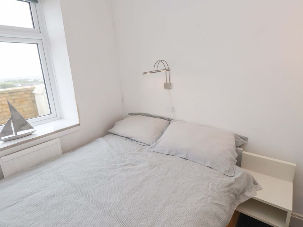 A bedroom with a bed and pillows at Sea Views No 8 Plas Darien Trearddur Bay