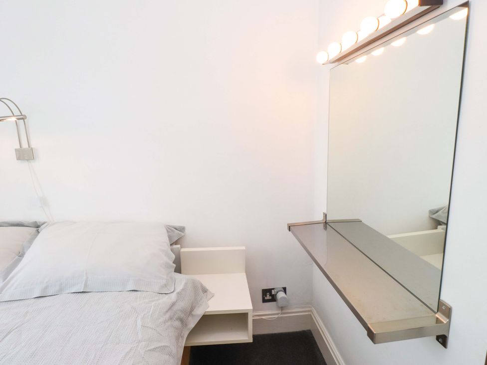 A bedroom with a bed and a mirror at Sea Views No 8 Plas Darien Trearddur Bay