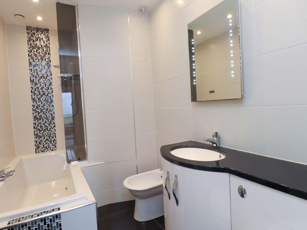 A bathroom with a bathtub, toilet, sink, and shower at Sea Views No 8 Plas Darien, Trearddur Bay