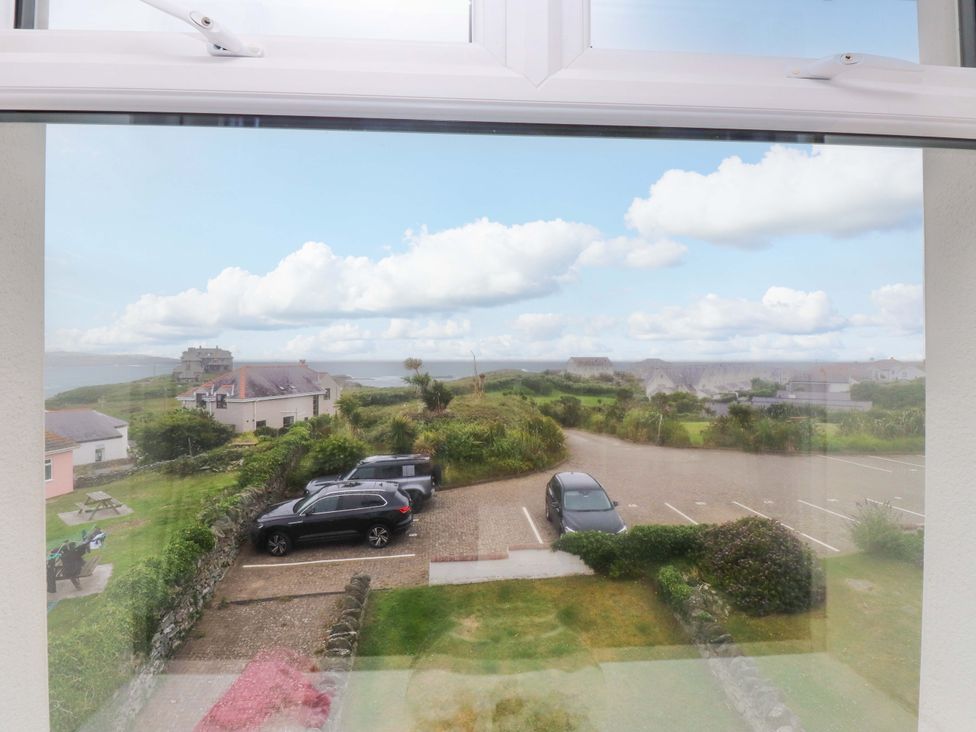 A view from a window showing cars in a parking lot and surrounding grass at Sea Views No 8 Plas Darien in Trearddur Bay