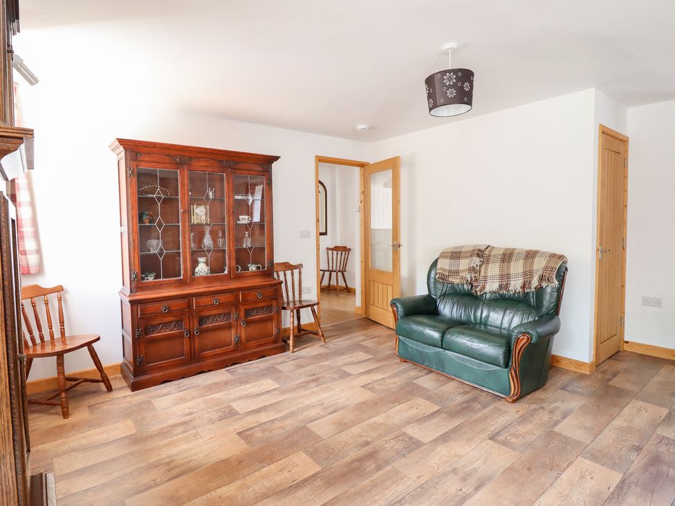 A living room with a cabinet and a sofa at Gwernffridd