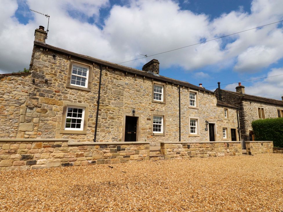 A stone building with windows and door at Rose Tree Cottage in Skipton