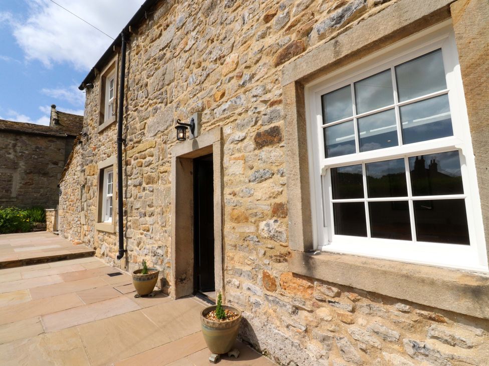 An exterior view of a stone cottage with a door and a window at Rose Tree Cottage in Skipton