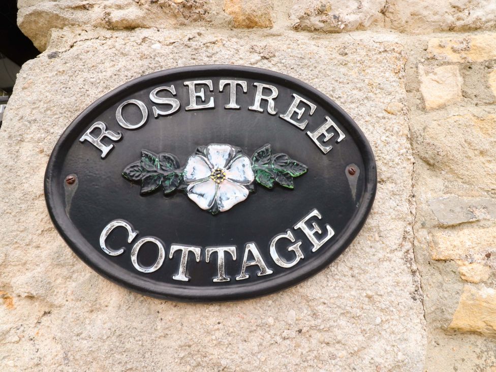 A nameplate with 'Rosetree Cottage' on a stone wall at Rosetree Cottage in Skipton