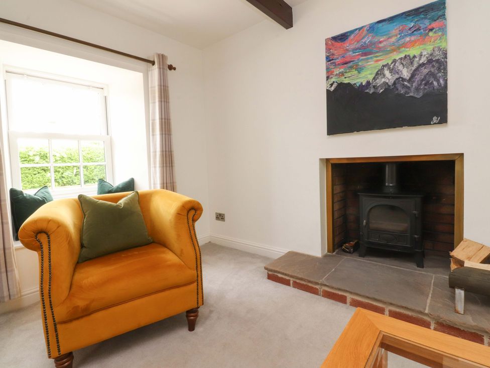 A living room with an armchair and a fireplace at Rose Tree Cottage in Skipton