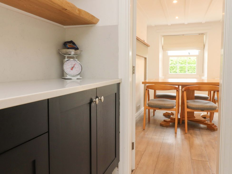 A kitchen with cabinets, scale, and dining table at Rose Tree Cottage in Skipton