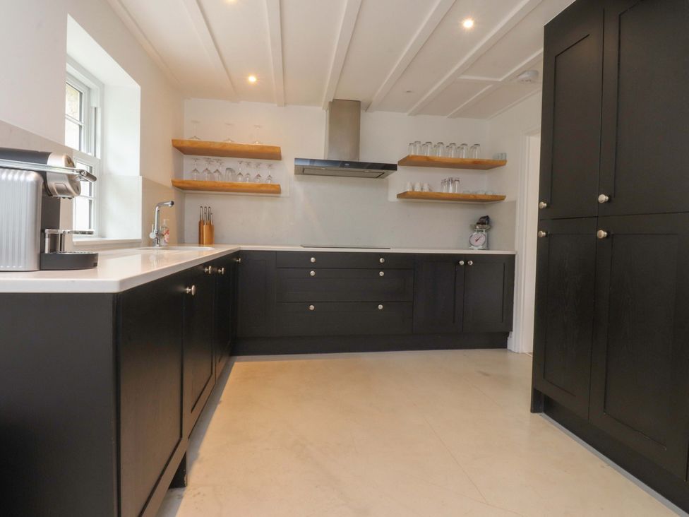 A kitchen with cabinets and shelf at Rose Tree Cottage in Skipton