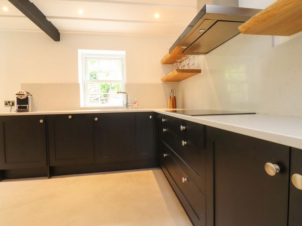 A kitchen with black cabinets and a window at Rose Tree Cottage in Skipton