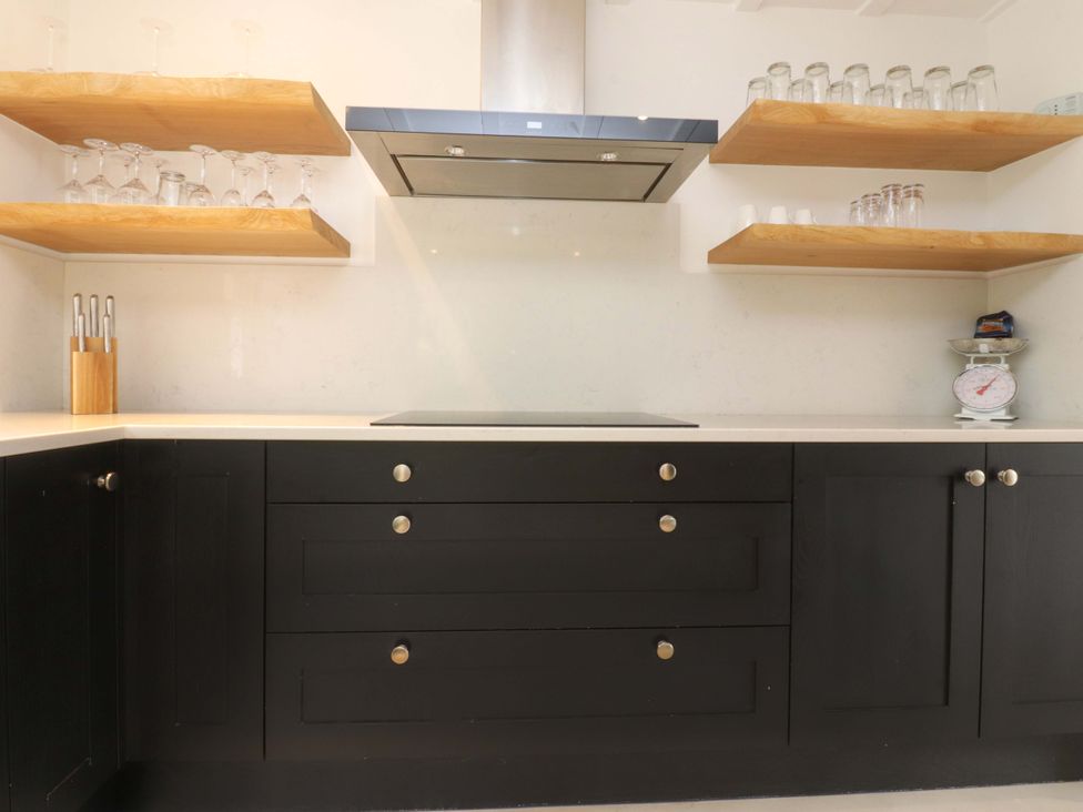 A kitchen with cabinets and shelves at Rose Tree Cottage in Skipton