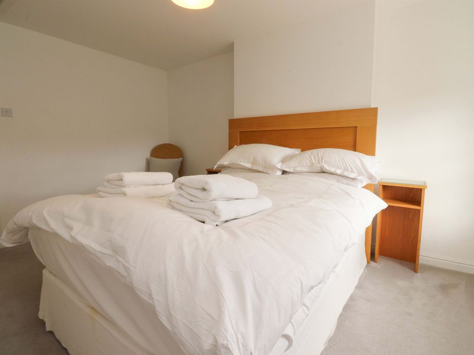 A bedroom with a bed and towels at Rose Tree Cottage in Skipton