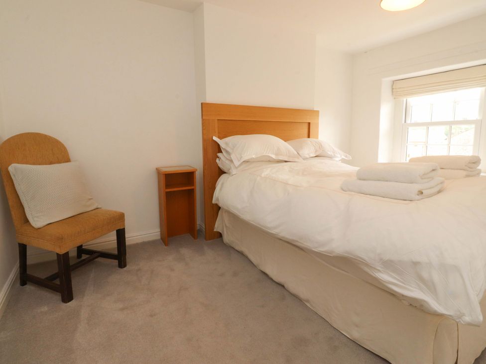 A bedroom with a bed, chair, nightstand and towels at Rose Tree Cottage, Skipton