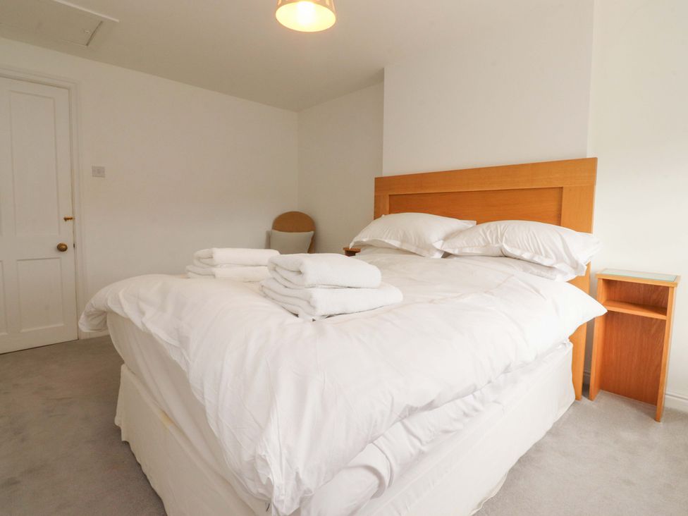 A bedroom with a bed and towels at Rose Tree Cottage in Skipton