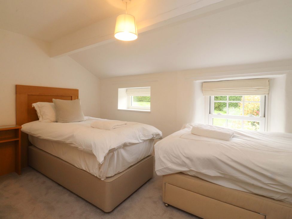 A bedroom with two beds and windows at Rose Tree Cottage in Skipton