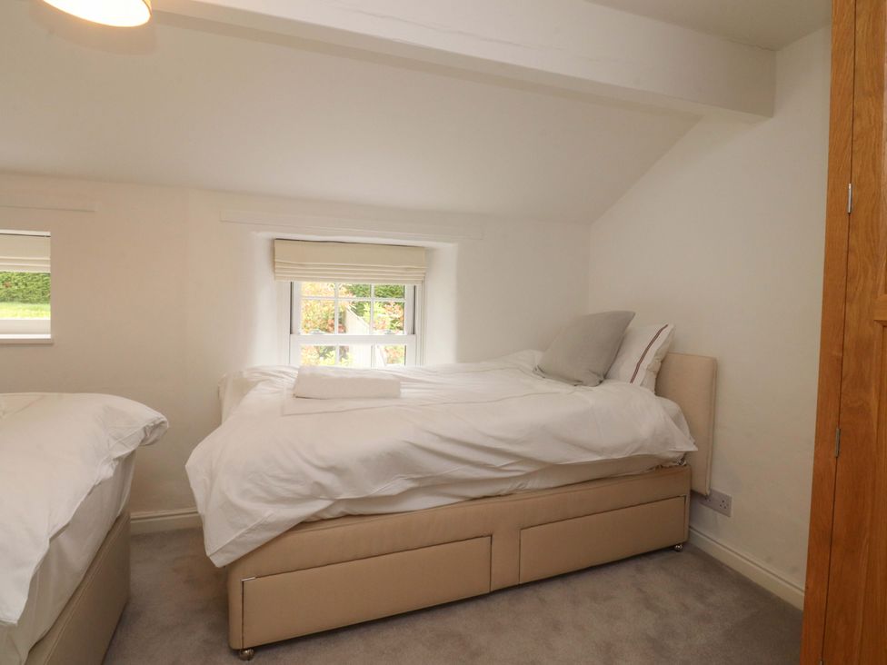 A bedroom with two beds and a window at Rose Tree Cottage in Skipton