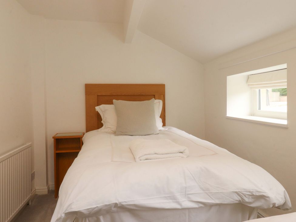 A bedroom with a bed and a window at Rose Tree Cottage in Skipton