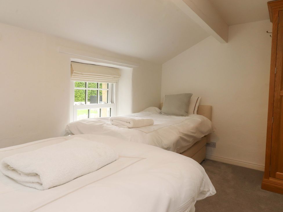 A bedroom with two beds and a window at Rose Tree Cottage in Skipton