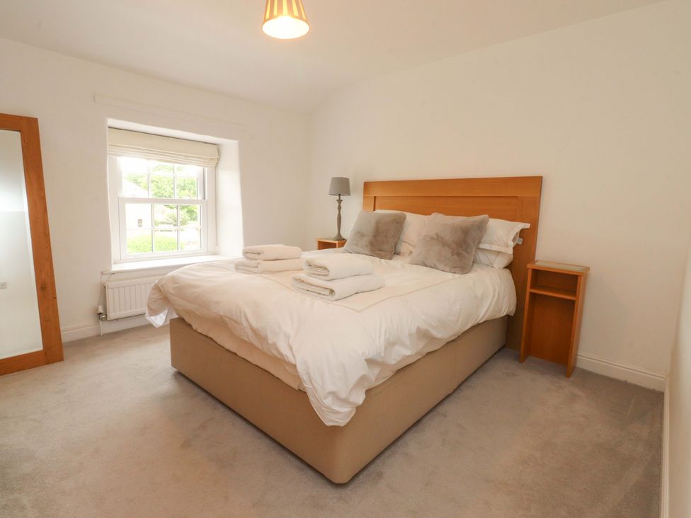 A bedroom with a bed and bedside table at Rose Tree Cottage in Skipton
