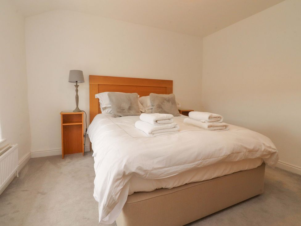 A bedroom with a bed and bedside table at Rose Tree Cottage in Skipton