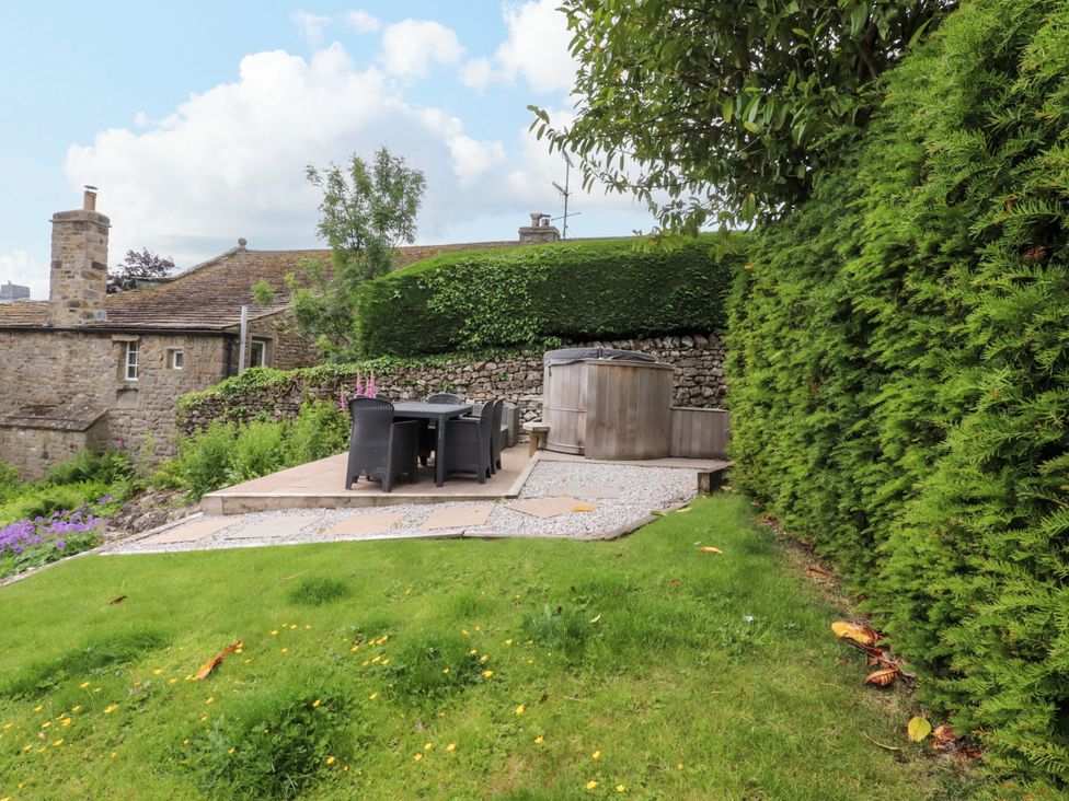 A garden with a dining area and hot tub at Rose Tree Cottage in Skipton
