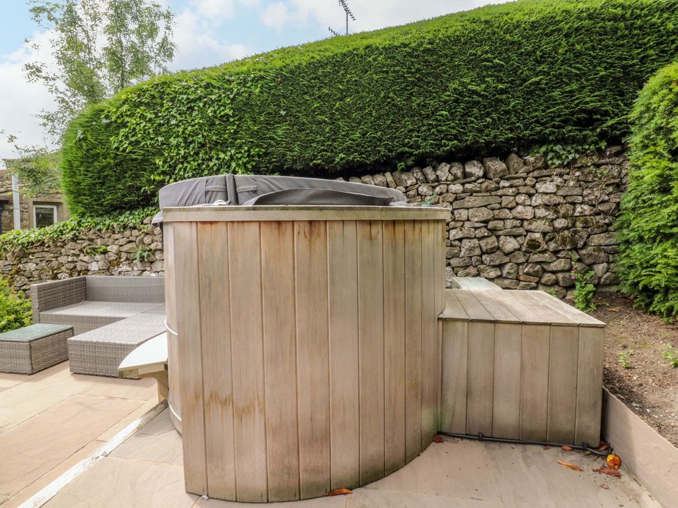 A hot tub with wooden decking and outdoor seating at Rose Tree Cottage in Skipton