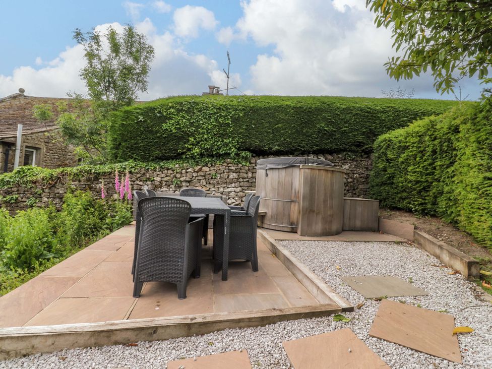 A garden with a table, chairs, and hot tub at Rose Tree Cottage in Skipton