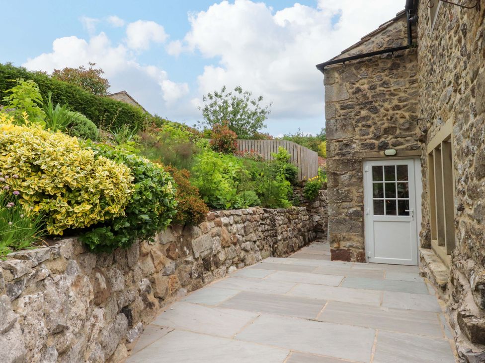 An outdoor pathway with a stone wall and plants at Rose Tree Cottage in Skipton