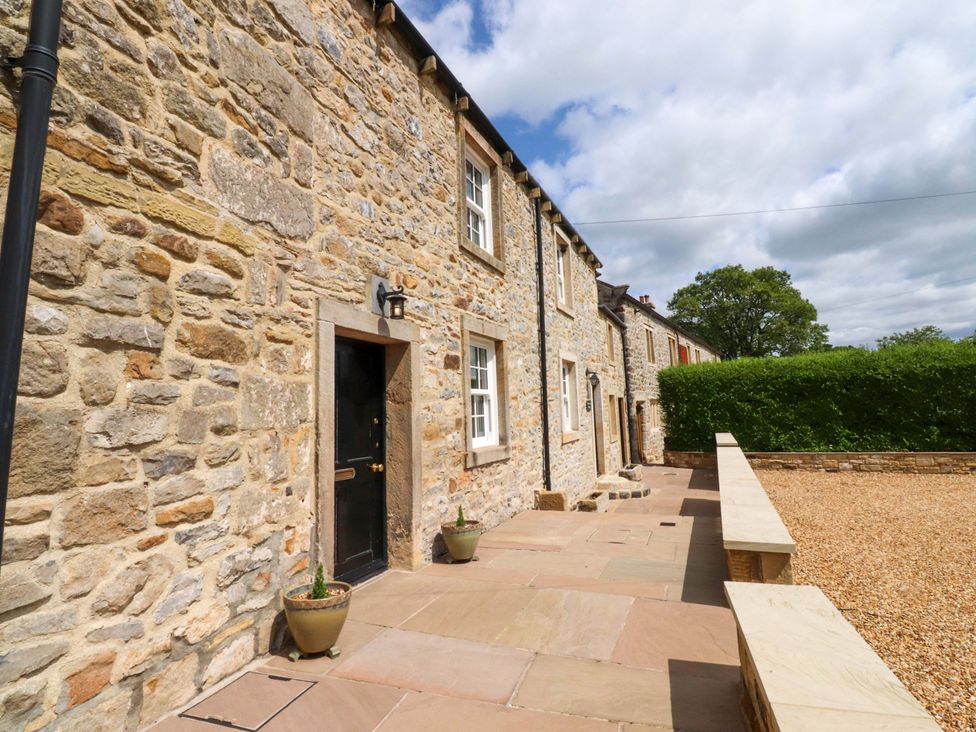 An outdoor area with stone wall and planters at Rose Tree Cottage Skipton