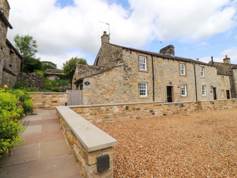 A stone house with a gravel driveway and pathway at Rose Tree Cottage in Skipton