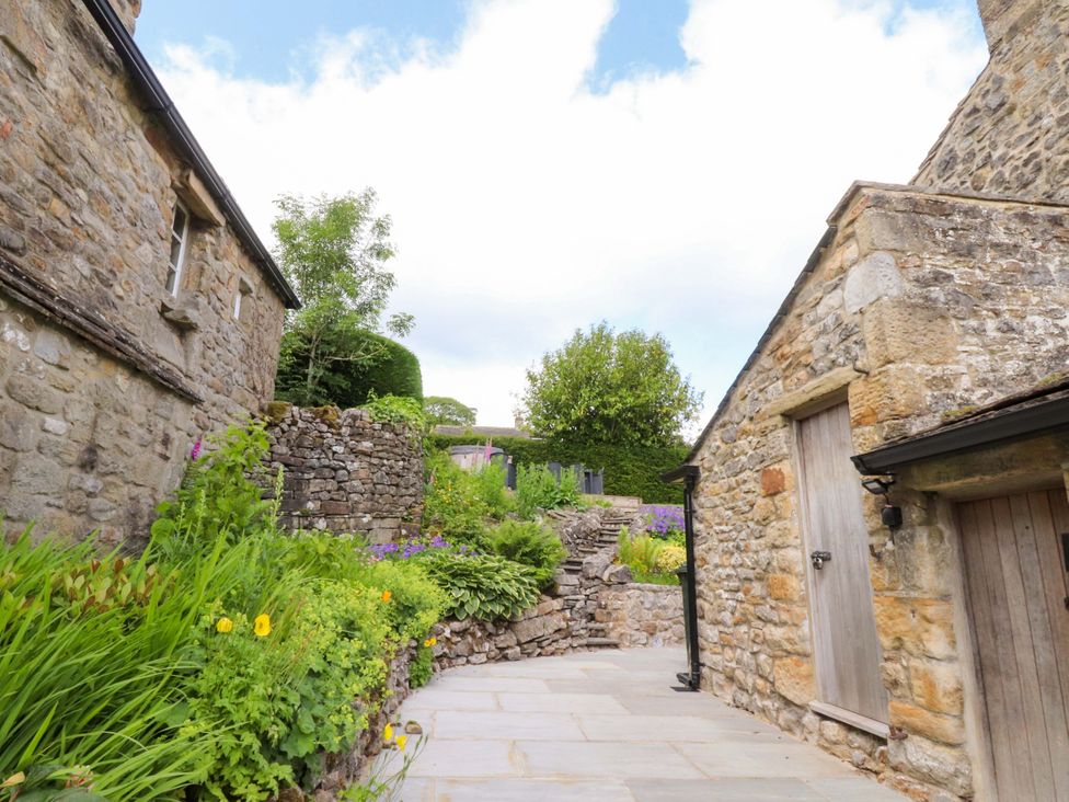 A garden with stone walls and flowers at Rose Tree Cottage in Skipton