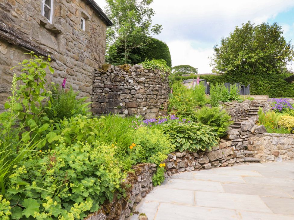 A garden with stone wall and plants at Rose Tree Cottage in Skipton
