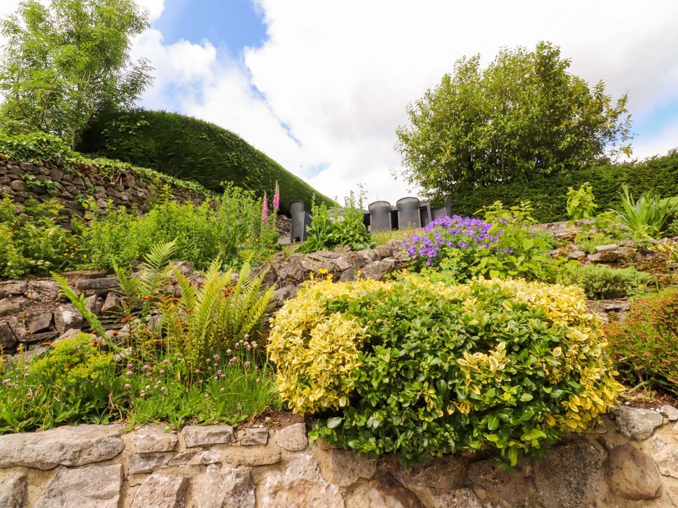 A garden with various plants and a stone wall at Rose Tree Cottage in Skipton