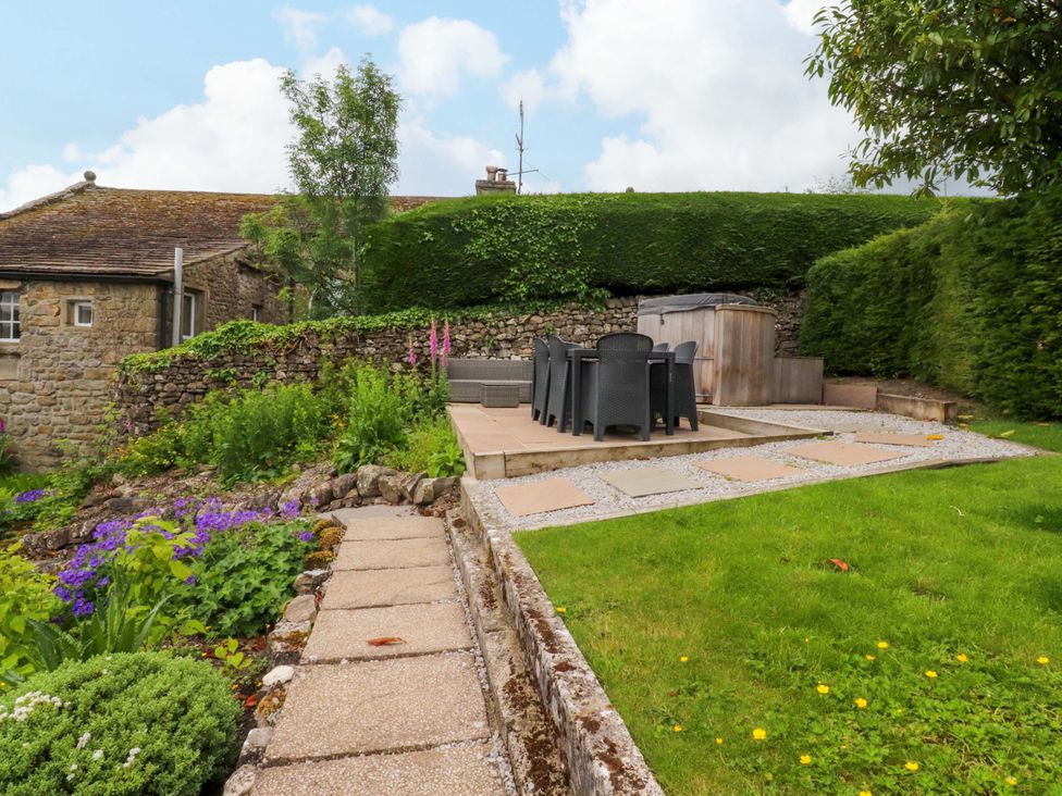 A garden with a table and chairs and a hot tub at Rose Tree Cottage in Skipton