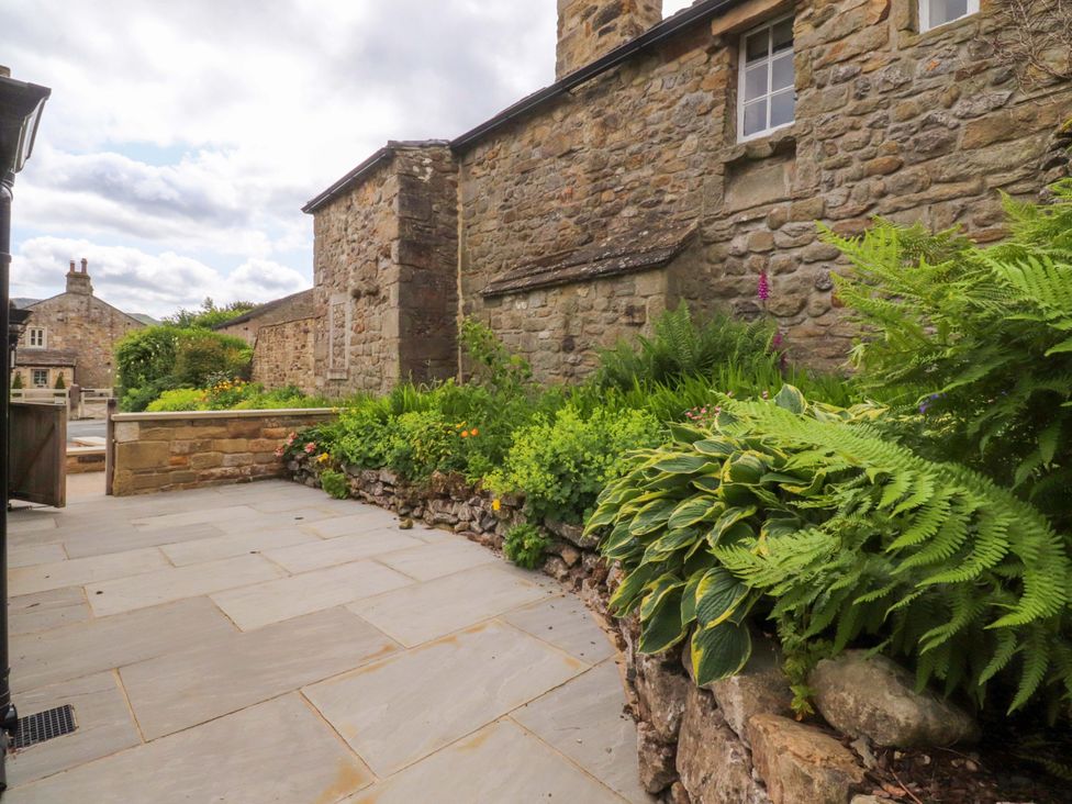 A garden area with a stone wall and plants at Rose Tree Cottage in Skipton