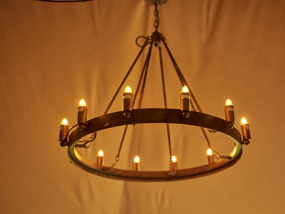 A circular chandelier with multiple lit bulbs hanging from the ceiling at Bramley Lodge in Coxbridge near Glastonbury