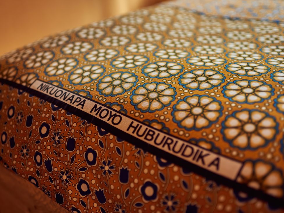 A close up of a patterned fabric with the words NIKUONAPA MOYO HUBURUDIKA printed on it