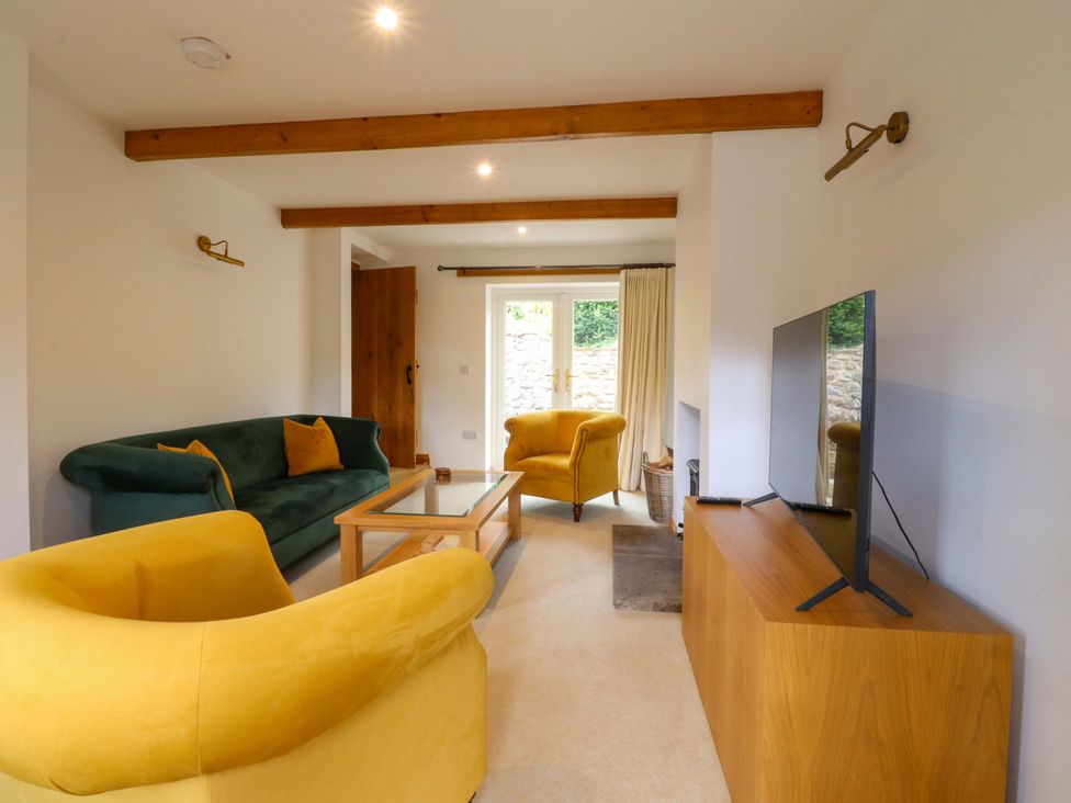 A living room with a green sofa and yellow armchairs at Rowan Tree Cottage in Skipsea
