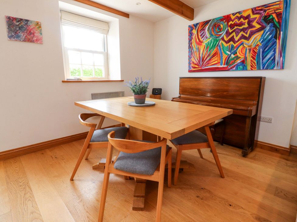 A dining room with a table and chairs and a piano at Rowan Tree Cottage in Skipsea