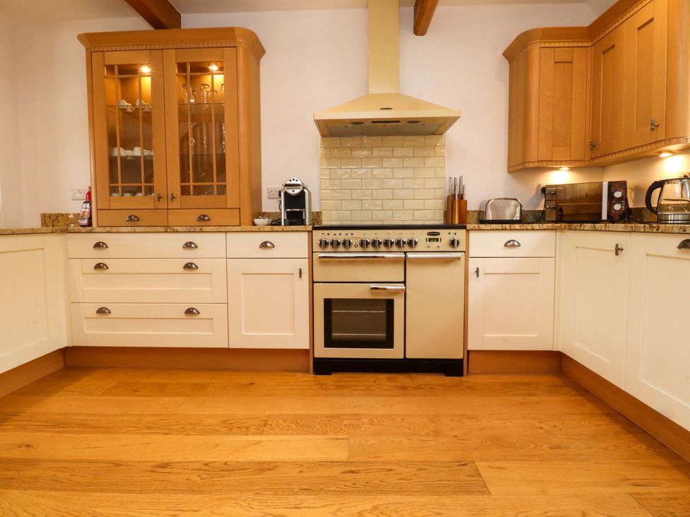 A kitchen with cabinets and an oven at Rowan Tree Cottage Skipsea