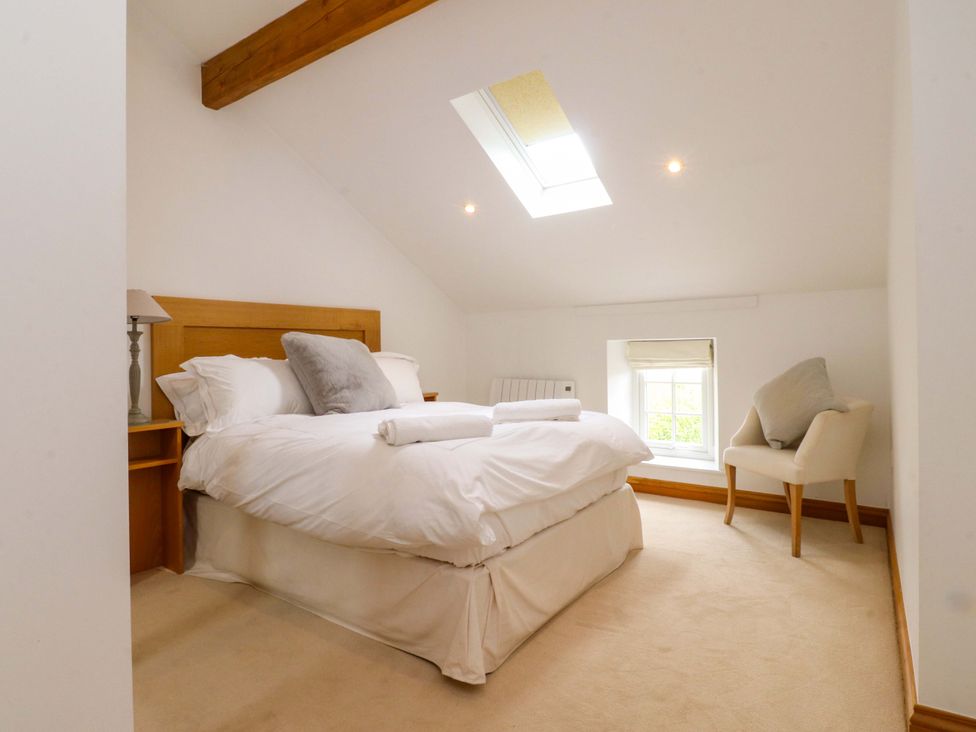 A bedroom with a bed and chair at Rowan Tree Cottage in Skipsea