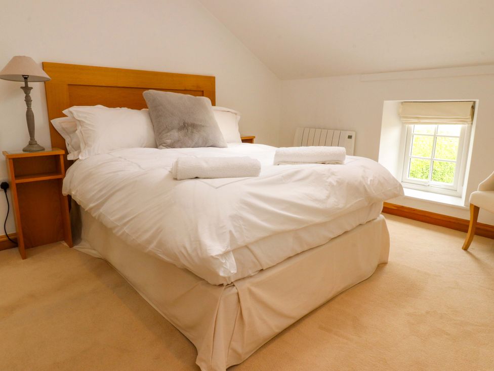 A bedroom with a bed and nightstand at Rowan Tree Cottage in Skipsea