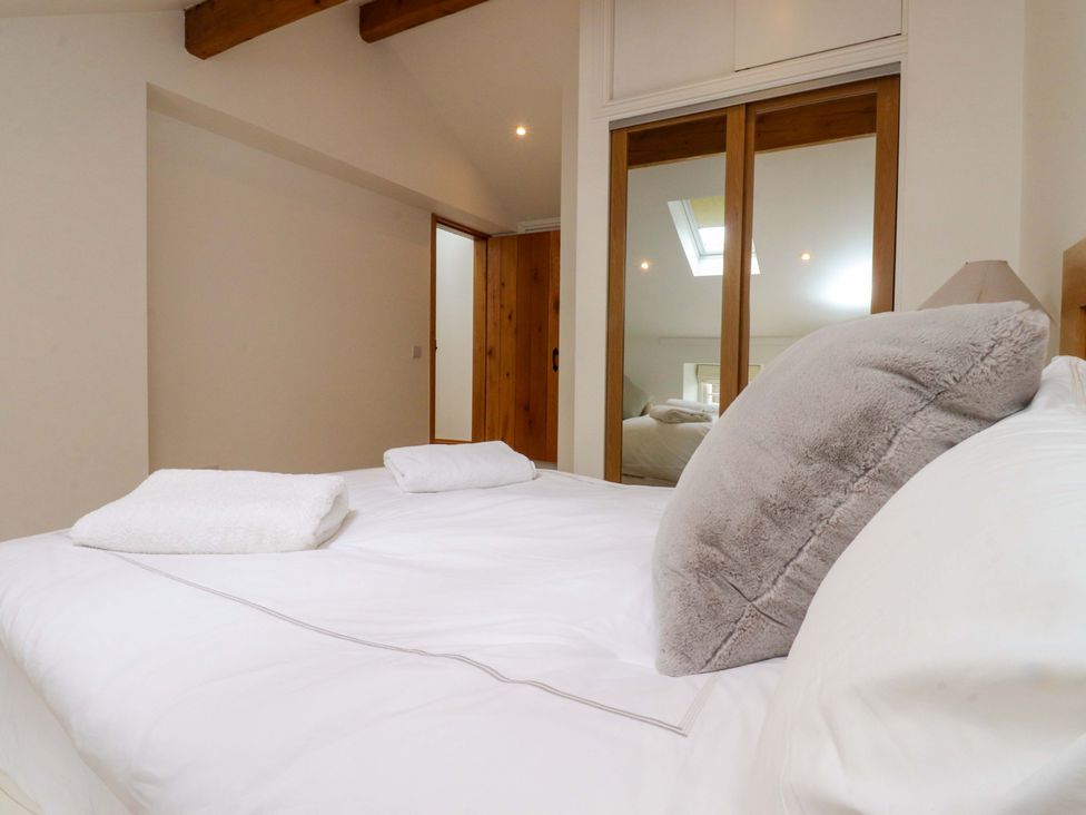 A bedroom with a bed and mirror at Rowan Tree Cottage Skipsea