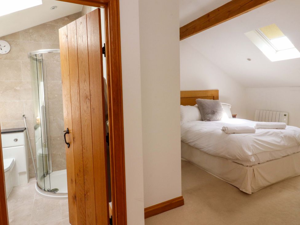 A bathroom with shower and toilet and a bedroom with bed at Rowan Tree Cottage Skipsea