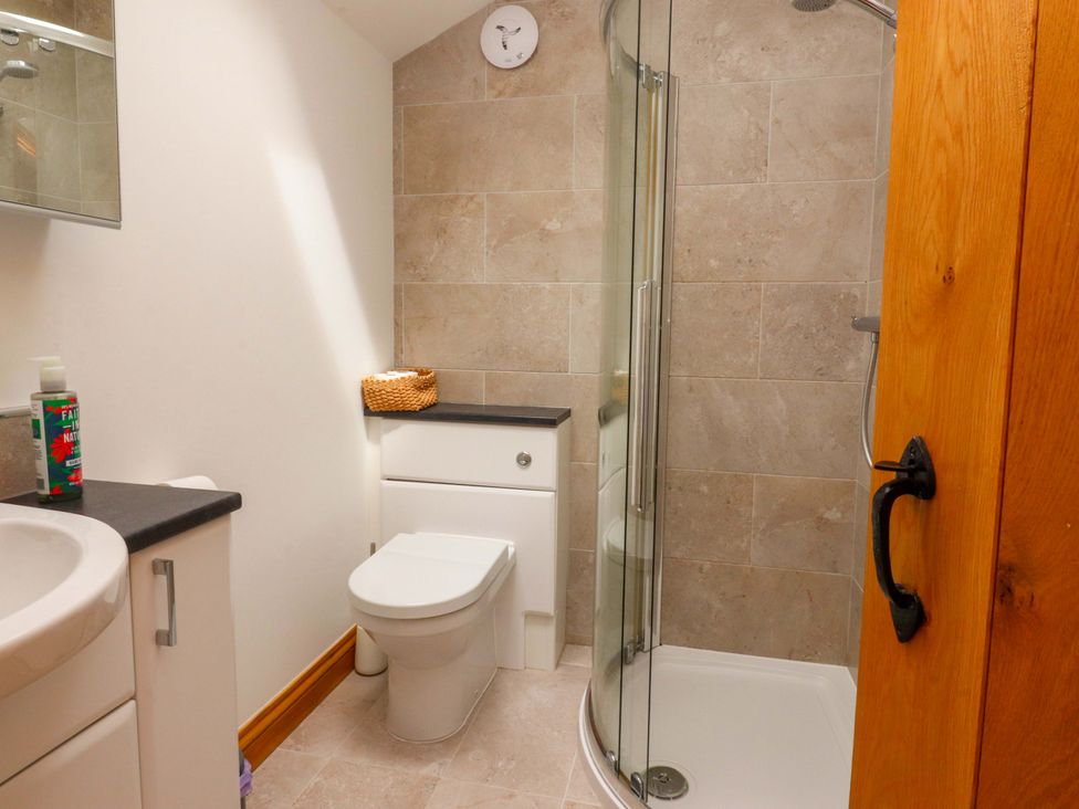 A bathroom with a shower, sink, and toilet at Rowan Tree Cottage Skipsea