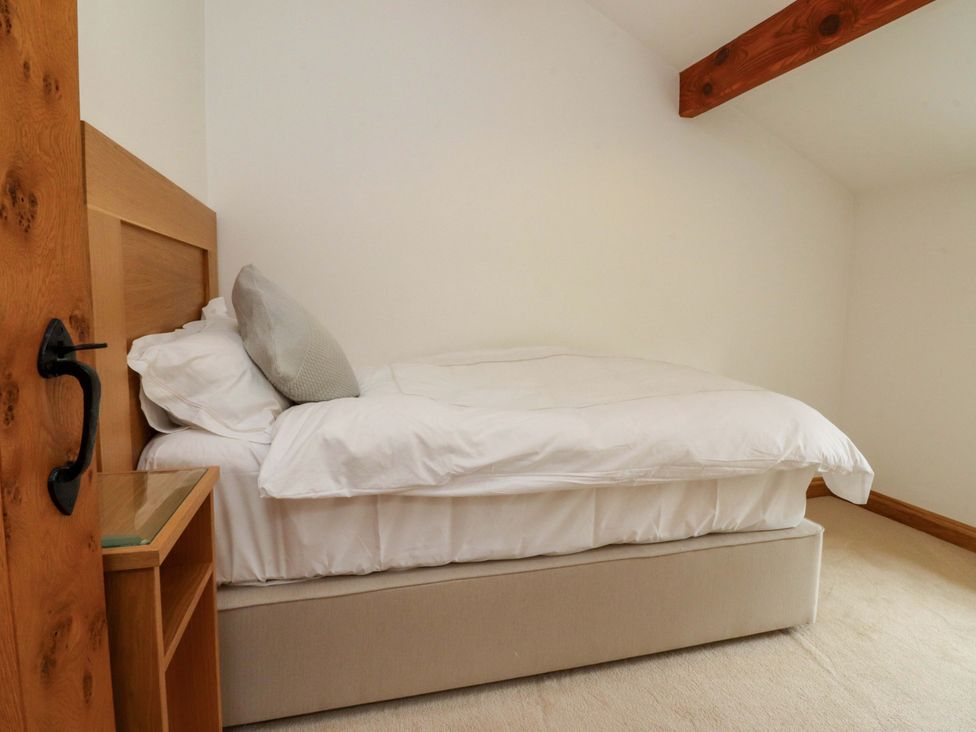 A bedroom with a bed and nightstand at Rowan Tree Cottage Skipsea
