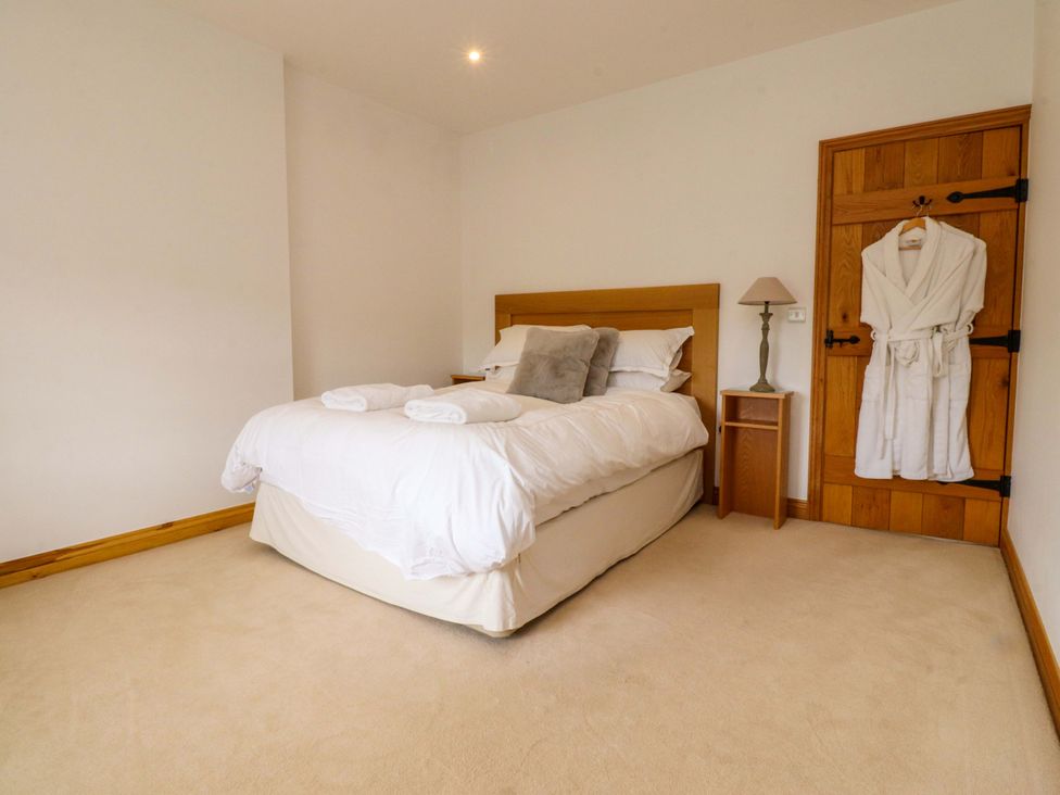 A bedroom with a bed and nightstand at Rowan Tree Cottage in Skipsea