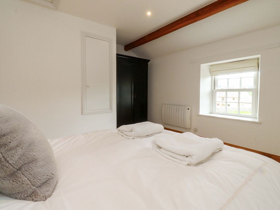 A bedroom with a bed and wardrobe at Rowan Tree Cottage in Skipsea