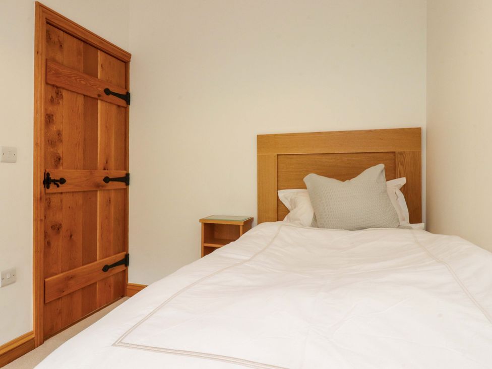 A bedroom with a single bed and wooden door at Rowan Tree Cottage in Skipsea